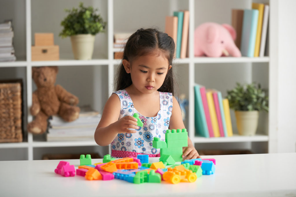 Little Asian girl playing with plastic cubes