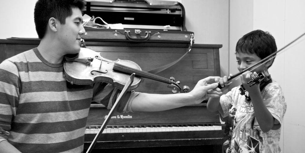 A violin teacher in a lesson with a young student